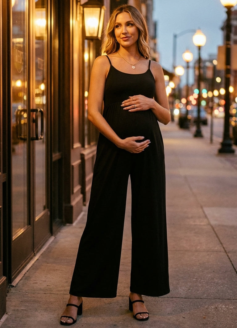 Woman in a black jumpsuit standing on a city street at dusk.
