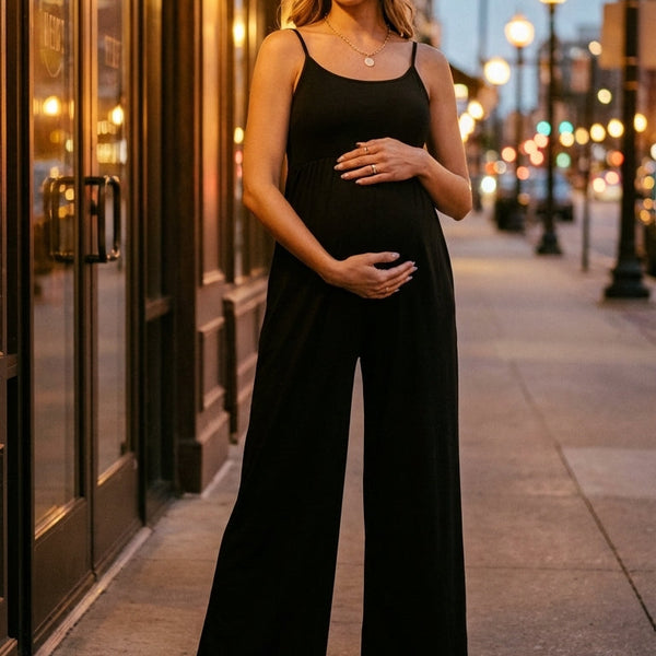 Woman in a black jumpsuit standing on a city street at dusk.